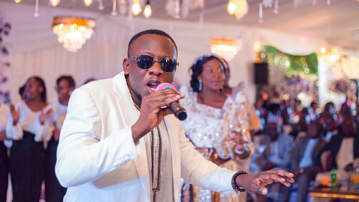 Singer in sunglasses performing at lively wedding celebration indoors.
